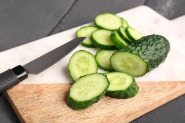 Koyu ahşap arka planda taze kesilmiş salatalıklı tahta.