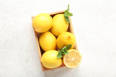 Taze limonlu ahşap kutu ve grunge beyaz arka planda nane.
