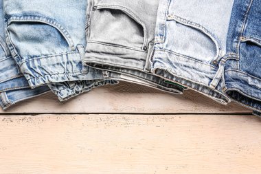 Ahşap arka planda farklı tarz kot pantolon, yakın plan.