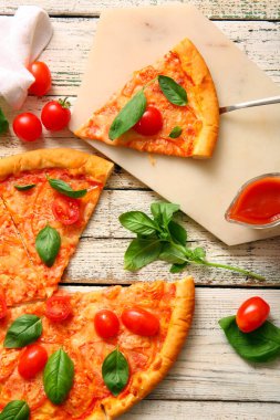 Beyaz ahşap arka planda lezzetli pizza margaritası olan bir pano.