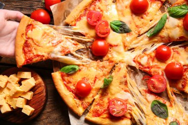Tahta masada lezzetli bir pizza dilimi yiyen bir kadın.