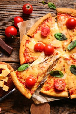 Ahşap masada lezzetli bir pizza margaritası ve fırın kağıdı.