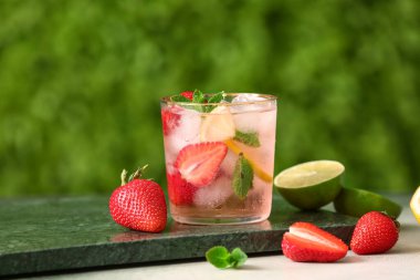 Dışarıdaki beyaz masada bir bardak çilekli limonata.