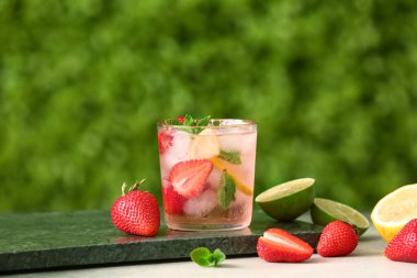 Dışarıdaki beyaz masada bir bardak çilekli limonata.