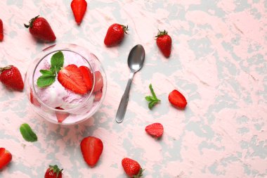 Arkaplanda bir kase çilekli dondurma ve kaşık.