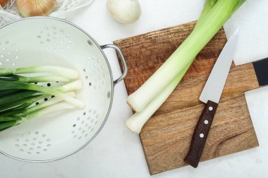 Tahta ve kevgir. Beyaz arka planda farklı soğan çeşitleri var.