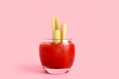 Pembe arka planda kerevizli bir bardak Bloody Mary.
