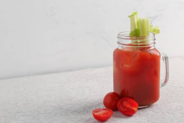 Mason kavanozu içinde kereviz ve domatesler beyaz masada.