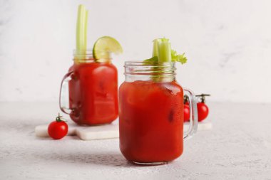 Kanlı Mary kavanozları, kereviz ve beyaz masada domatesler.