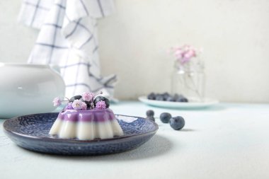 Böğürtlenli panna cotta tabakları ve beyaz masada güzel çigila çiçekleri.