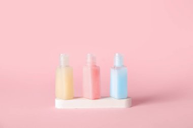 Pembe arka planda kozmetik ürünleri şişeleriyle sıva podyumu