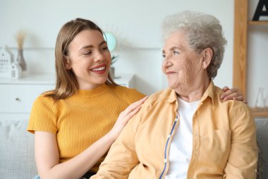 Büyükannesiyle evdeki kanepede oturan genç bir kadın.