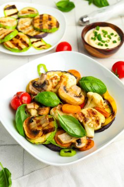 Izgara sebzeli tabaklar ve beyaz fayanslı ekşi krema.