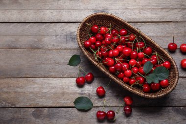 Gri ahşap arka planda kirazlı hasır kase.