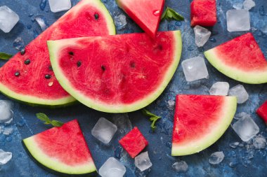 Mavi zemin üzerinde naneli ve buz küplü taze karpuz parçaları.