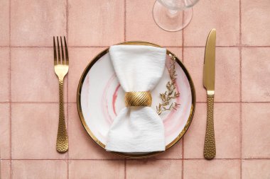 Bej kaplama arka planda altın yapraklı ve çatal bıçaklı zarif bir masa.