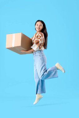 Mavi arka planda parsel atlayan genç Asyalı kadın.