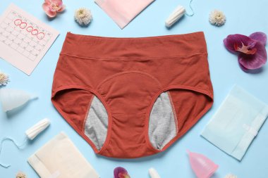 Dönem külotlu, pedli, tamponlu, regl bardaklı ve mavi arka planda güzel çiçekli kompozisyon