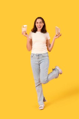 Sarı arka planda patates kızartması olan mutlu genç bir kadın.