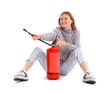 Beyaz arka planda oturan yangın söndürücüsü olan genç bir kadın.