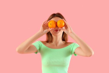 Pembe arka planda portakalları olan komik bir genç kadın.