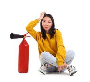 Beyaz arka planda oturan yangın söndürücüsü olan genç Asyalı kadın.