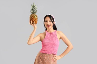 Gri arka planda ananaslı güzel bir Asyalı kadın.