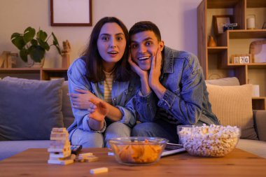 Akşamları evdeki kanepede televizyon izleyen genç bir çift.