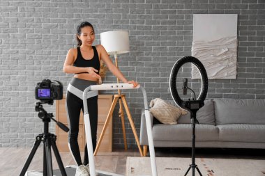 Koşu bandı eğitim videosundaki Asyalı kadın spor blogcusu