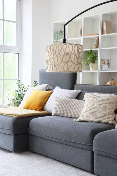 Interior of stylish living room with cozy grey sofa near big window
