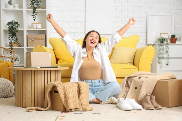 Happy young Asian woman with parcels at home