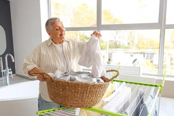 Senior woman with laundry basket at home