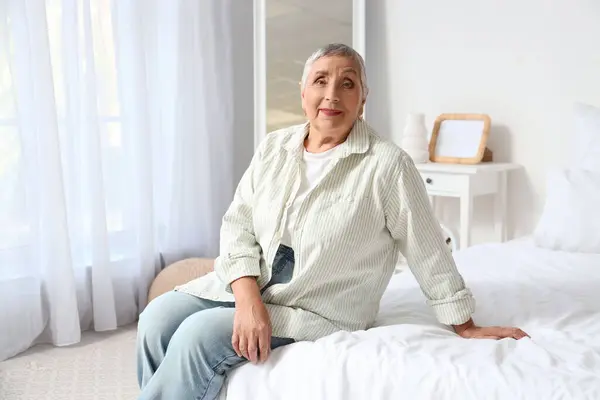 Senior woman sitting on bed in bedroom