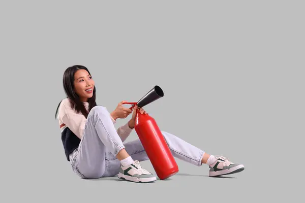Ung Asiatisk Kvinna Med Brandsläckare Sitter Mot Grå Bakgrund — Stockfoto