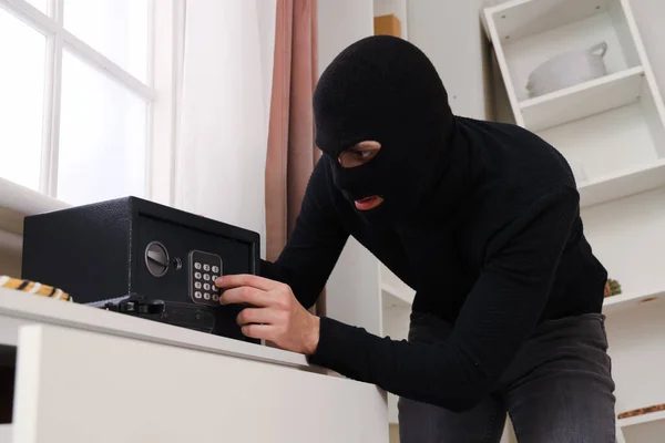 Male thief breaking into safe in room