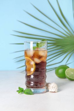 Beyaz masada soğuk Küba kokteyli, palmiye yaprağı ve deniz kabuğu.