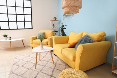 Oturma odasında rahat koltuk, kanepe ve masalar.