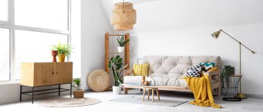 Konforlu kanepe, ahşap dolap ve dekorla aydınlık oturma odasının içinde.