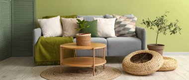 Rahat gri kanepesi, çiçekleri ve ahşap sehpası olan oturma odasının içinde.