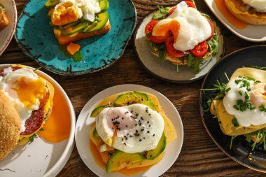 Ahşap arka planda lezzetli yumurtalı Benedict tabakları.