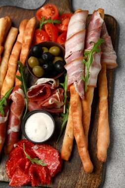 Hafif arka planda domuz pastırması olan lezzetli İtalyan Grissini tahtası.