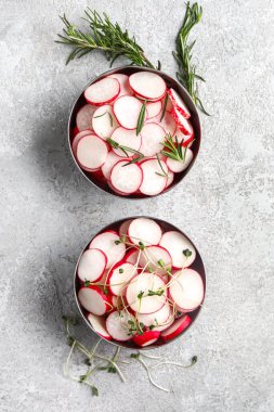 Gri grunge arka planda taze turp ve mikroyeşillik dilimleri olan kaseler.