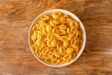 Ahşap zemin üzerinde çiğ koni makarna ile kase