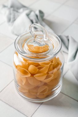 Beyaz karo zemin üzerinde çiğ koni makarna ile kavanoz