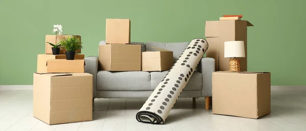 Sofa with rolled carpet and cardboard boxes in living room on moving day
