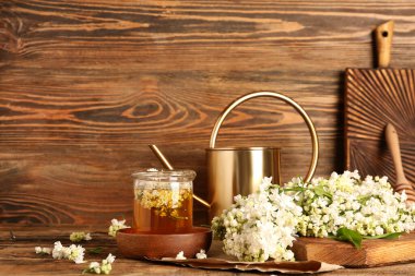 Sulama tenekesi, bal kavanozu ve ahşap masa üzerinde beyaz leylak dalları olan kompozisyon