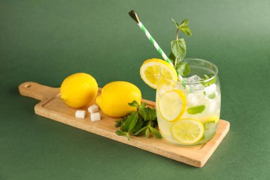Yeşil zemin üzerinde bir bardak taze limonata olan tahta.