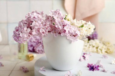 Beyaz fayansın yanında duran güzel kokulu leylak çiçekleri.