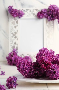 Güzel kokulu leylak çiçekleri tabağı ve grunge duvarının yanındaki beyaz fayans üzerinde çerçeve