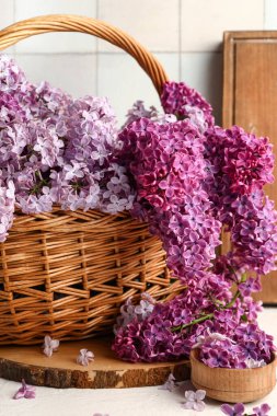 Güzel kokulu leylak çiçekleri ve beyaz fayansların yanında ahşap tahtalarla dolu bir sepet.